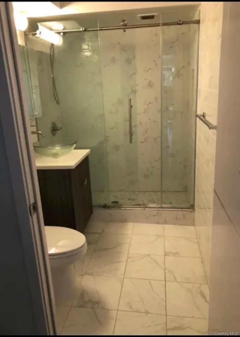 Full bath featuring vanity and a marble finish shower Full bath featuring vanity and a marble finish shower