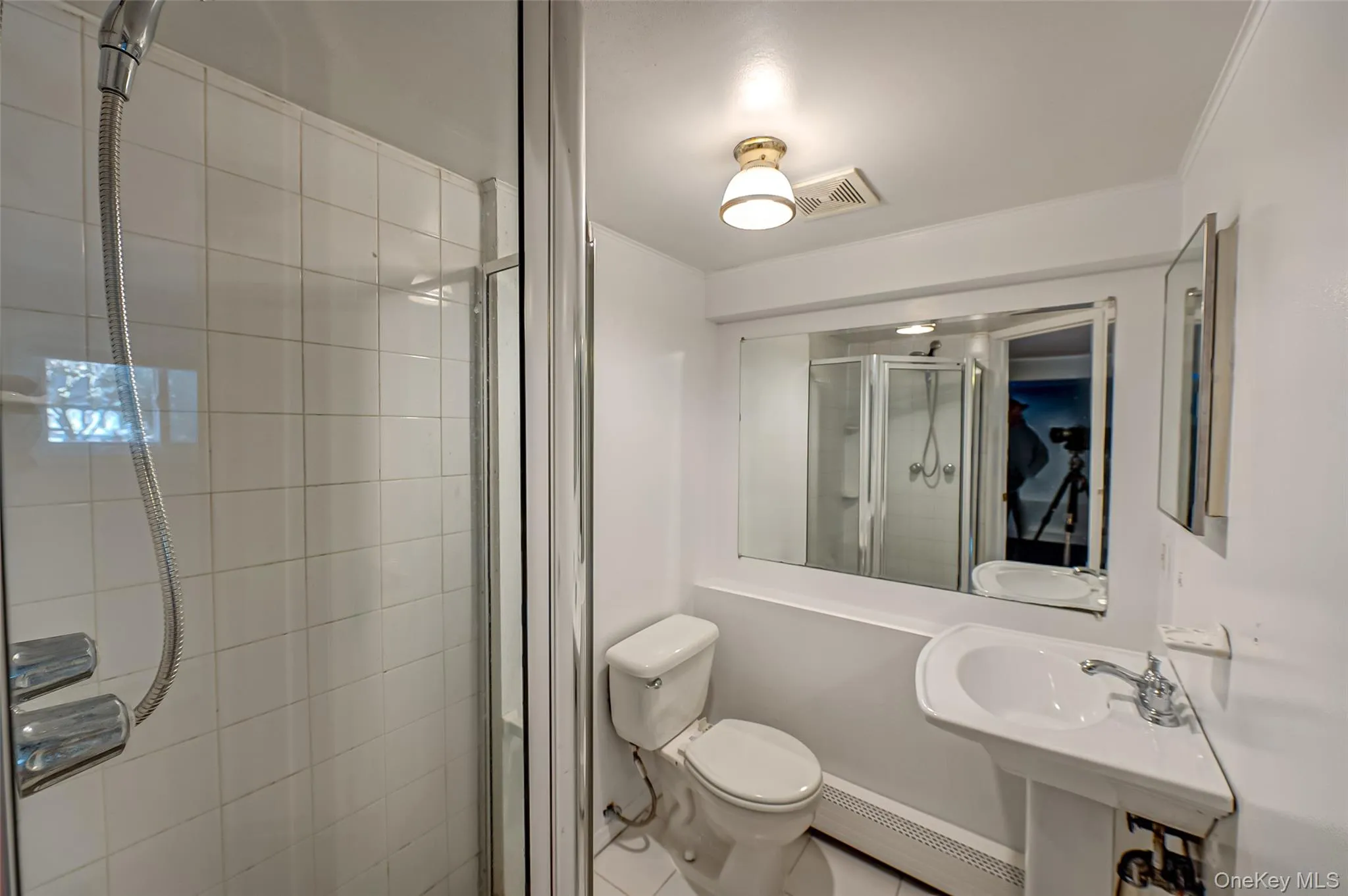 Bathroom with tile patterned floors, toilet, ornamental molding, baseboard heating, and a shower with shower door Bathroom with tile patterned floors, toilet, ornamental molding, baseboard heating, and a shower with shower door