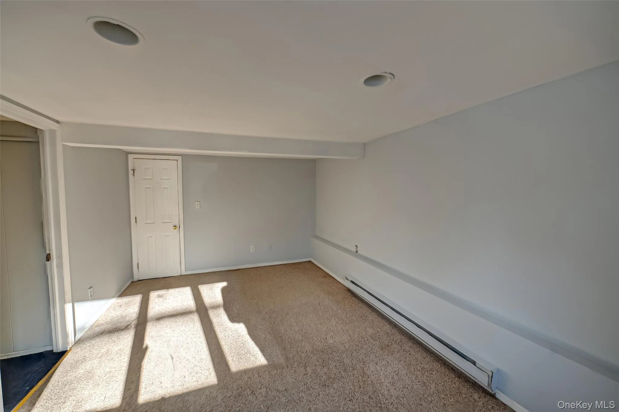 Unfurnished bedroom with carpet and baseboard heating Unfurnished bedroom with carpet and baseboard heating