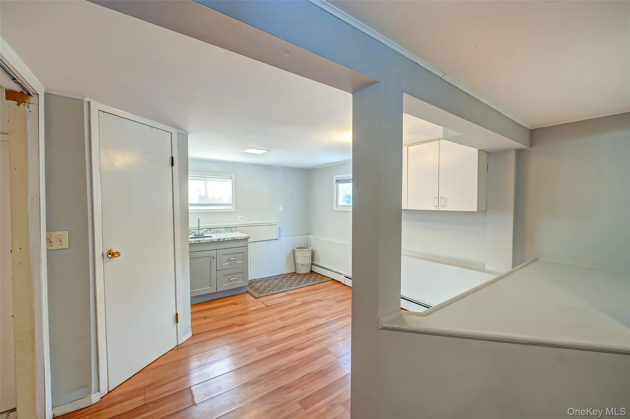 Laundry area featuring light hardwood / wood-style floors, a baseboard radiator, and sink Laundry area featuring light hardwood / wood-style floors, a baseboard radiator, and sink