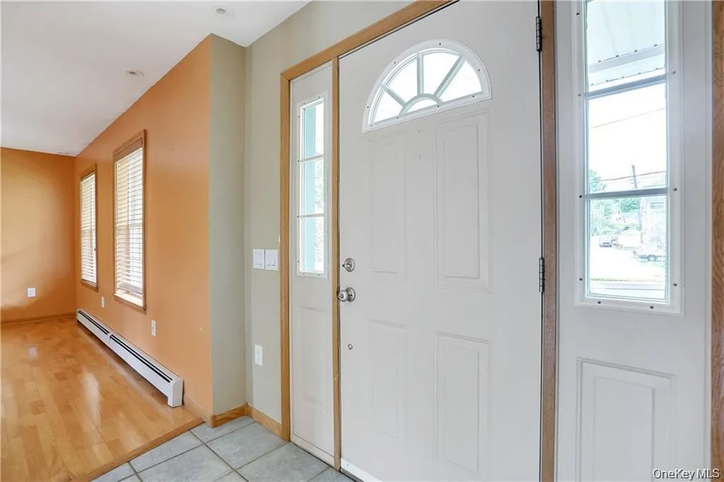 Foyer entrance with baseboard heating and light tile patterned flooring Foyer entrance with baseboard heating and light tile patterned flooring