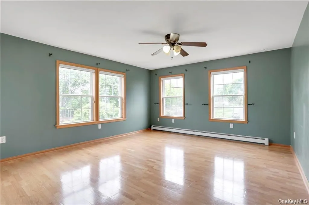 Spare room featuring a baseboard radiator, light wood finished floors, and a ceiling fan Spare room featuring a baseboard radiator, light wood finished floors, and a ceiling fan
