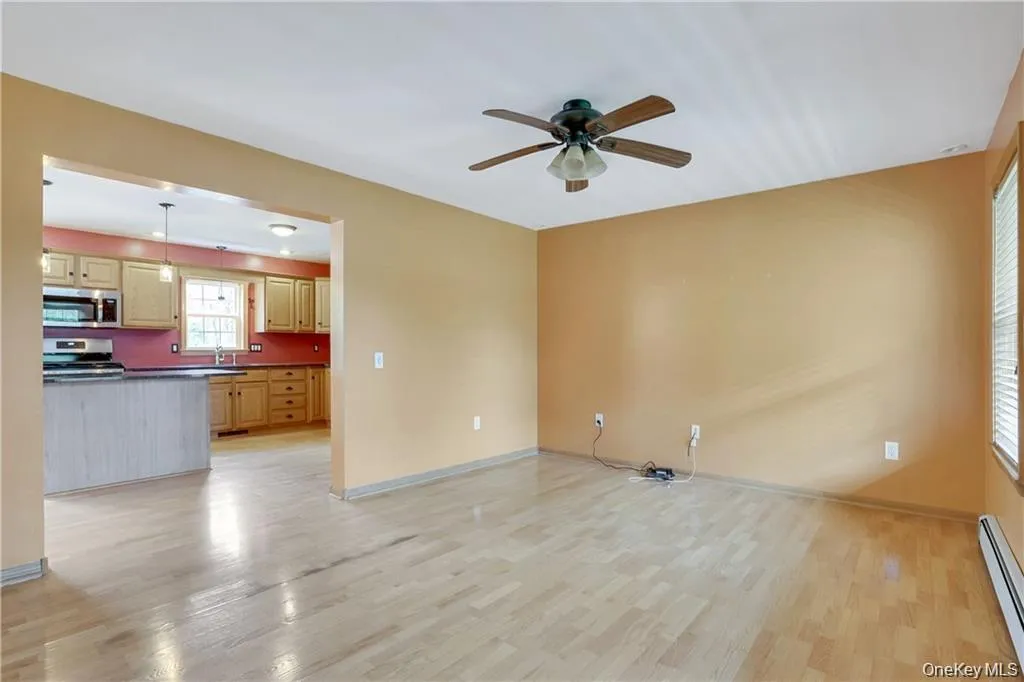 Unfurnished living room with light wood finished floors, a baseboard heating unit, and ceiling fan Unfurnished living room with light wood finished floors, a baseboard heating unit, and ceiling fan