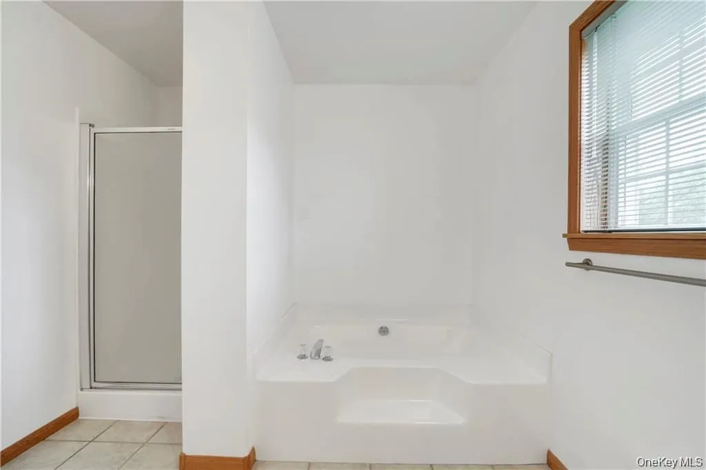 Bathroom with a bath, light tile patterned floors, and a stall shower Bathroom with a bath, light tile patterned floors, and a stall shower