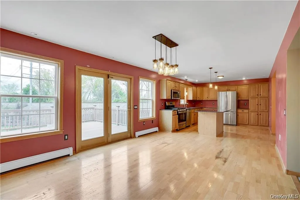Kitchen with a baseboard heating unit, appliances with stainless steel finishes, a center island, decorative light fixtures, and open floor plan Kitchen with a baseboard heating unit, appliances with stainless steel finishes, a center island, decorative light fixtures, and open floor plan