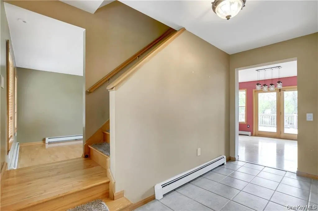 Entryway featuring a baseboard radiator, a baseboard heating unit, light tile patterned floors, and stairway Entryway featuring a baseboard radiator, a baseboard heating unit, light tile patterned floors, and stairway