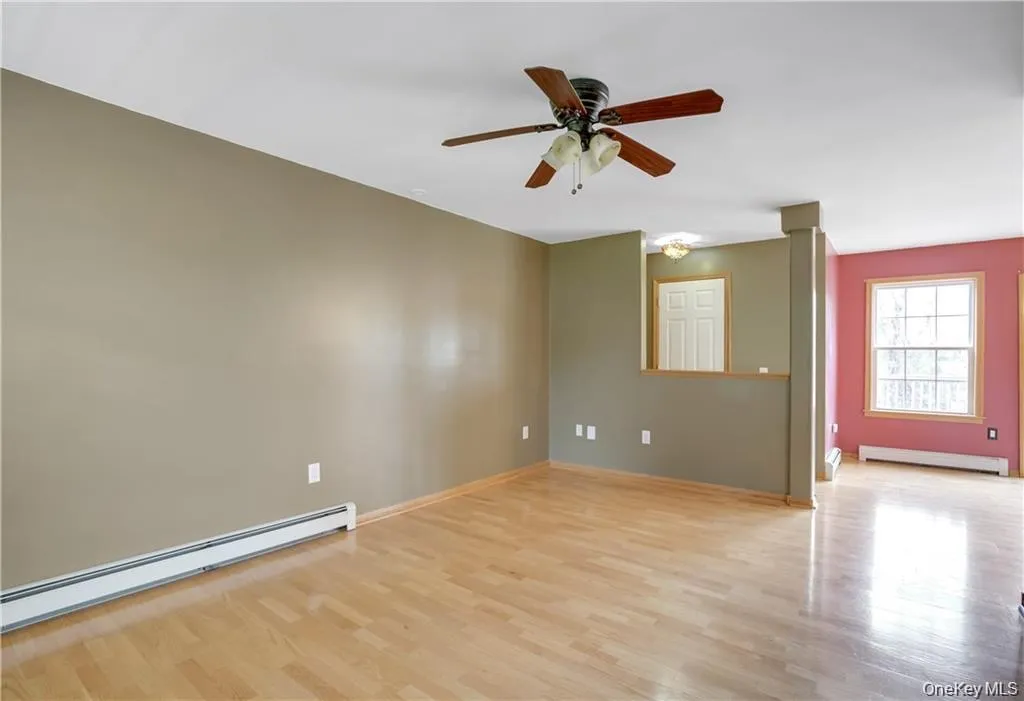 Empty room with baseboard heating, light wood-style flooring, a baseboard heating unit, and ceiling fan Empty room with baseboard heating, light wood-style flooring, a baseboard heating unit, and ceiling fan