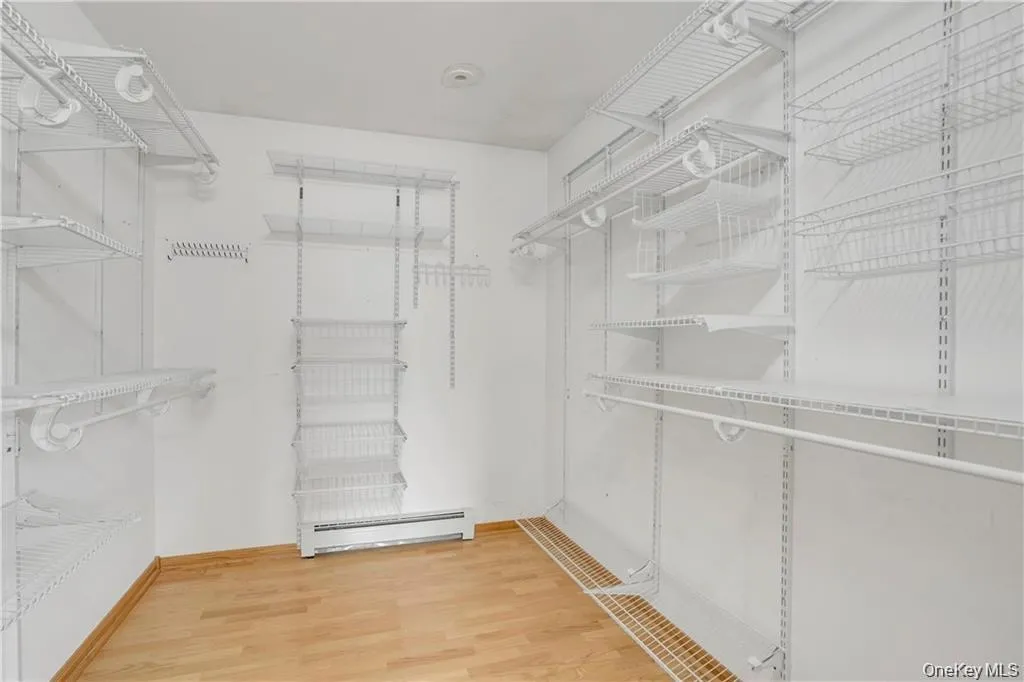Walk in closet featuring light wood-type flooring and baseboard heating Walk in closet featuring light wood-type flooring and baseboard heating