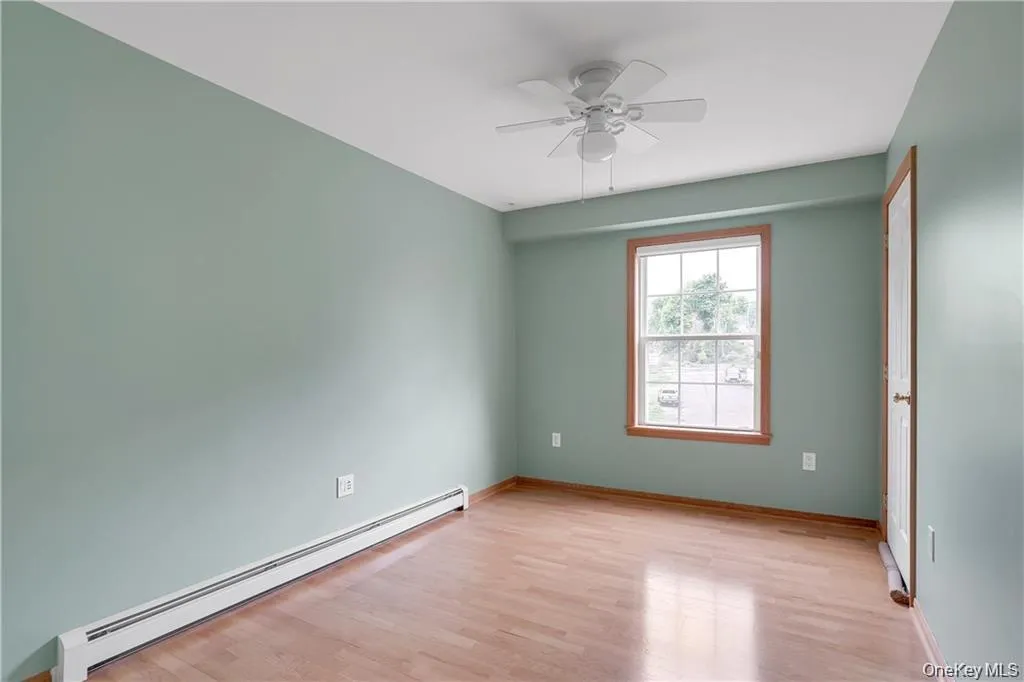 Empty room featuring a baseboard radiator, light wood-style floors, and ceiling fan Empty room featuring a baseboard radiator, light wood-style floors, and ceiling fan