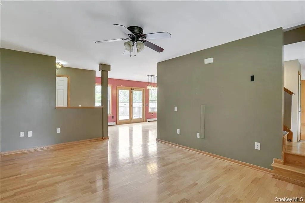 Unfurnished living room featuring light wood-style floors, stairway, and a ceiling fan Unfurnished living room featuring light wood-style floors, stairway, and a ceiling fan