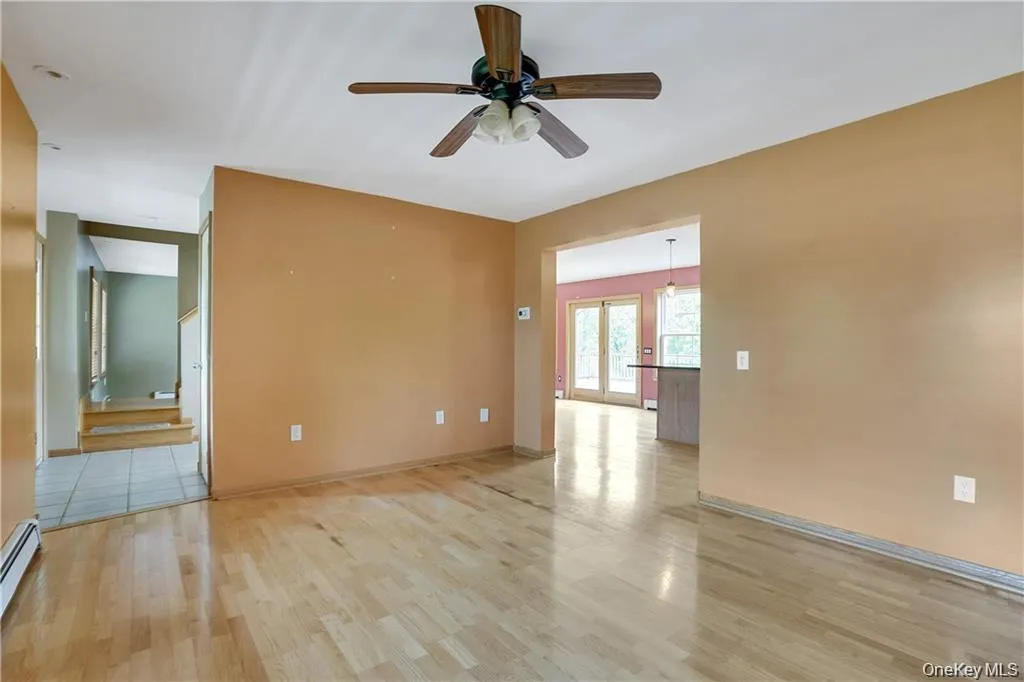 Spare room with light wood-type flooring, ceiling fan, french doors, and baseboard heating Spare room with light wood-type flooring, ceiling fan, french doors, and baseboard heating