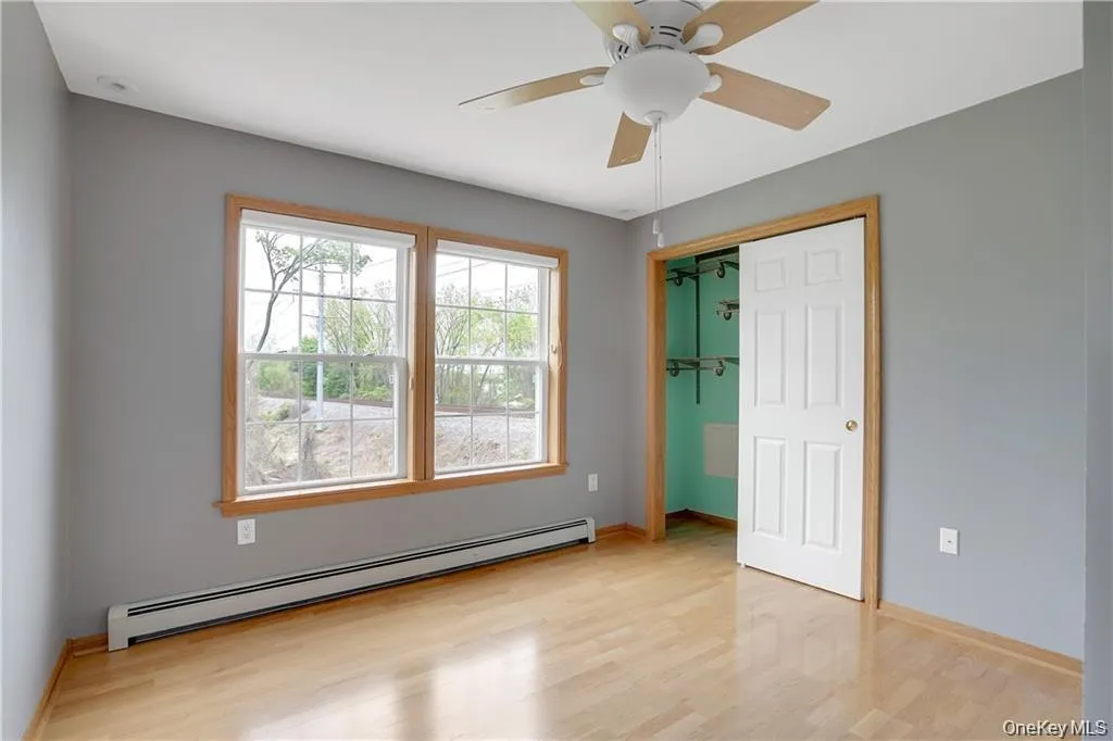 Unfurnished bedroom with a baseboard heating unit, ceiling fan, light wood finished floors, and a closet Unfurnished bedroom with a baseboard heating unit, ceiling fan, light wood finished floors, and a closet