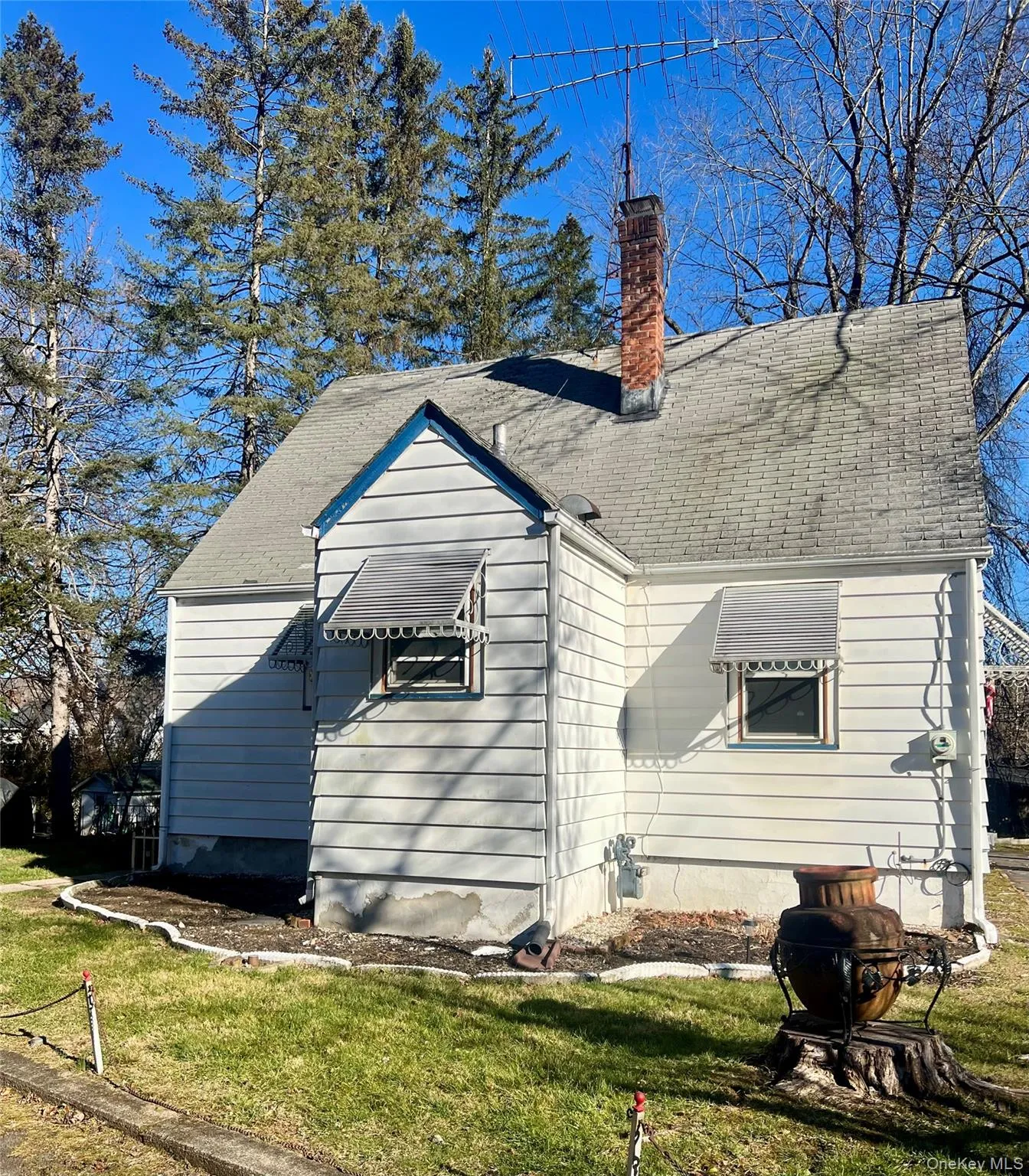 Back of property with a chimney, a yard, and roof with shingles Back of property with a chimney, a yard, and roof with shingles