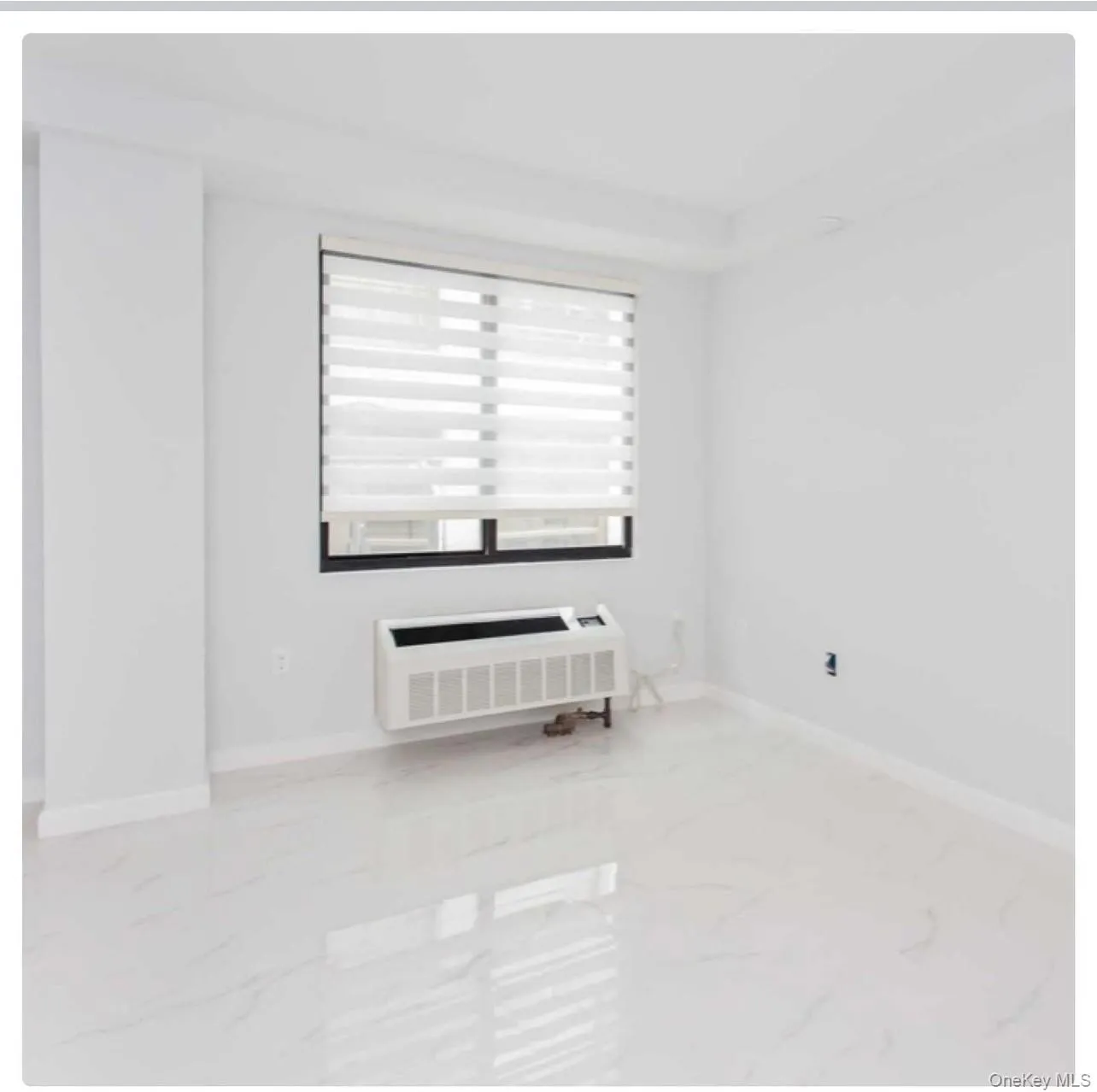 Empty room featuring light marble finish floors and radiator Empty room featuring light marble finish floors and radiator