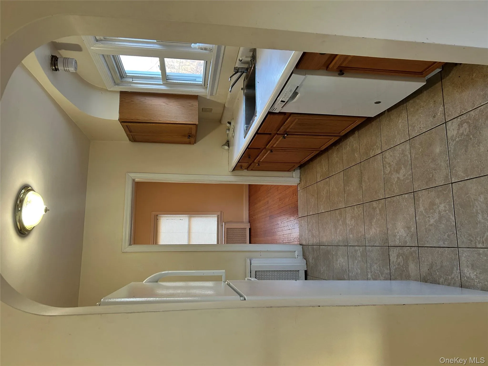 Kitchen with brown cabinets, arched walkways, light countertops, dishwasher, and healthy amount of natural light Kitchen with brown cabinets, arched walkways, light countertops, dishwasher, and healthy amount of natural light