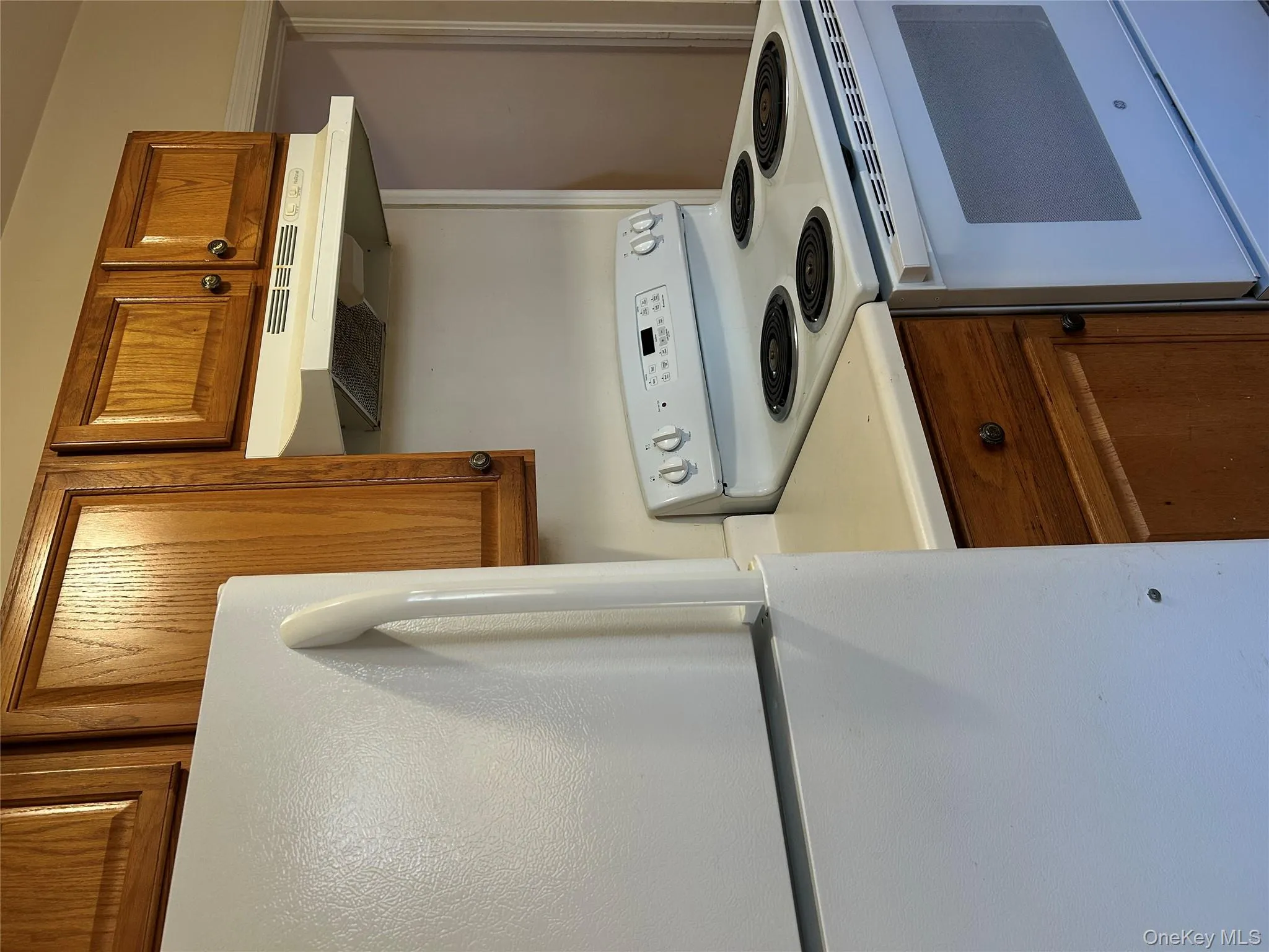 Kitchen featuring brown cabinets, white appliances, light countertops, and extractor fan Kitchen featuring brown cabinets, white appliances, light countertops, and extractor fan