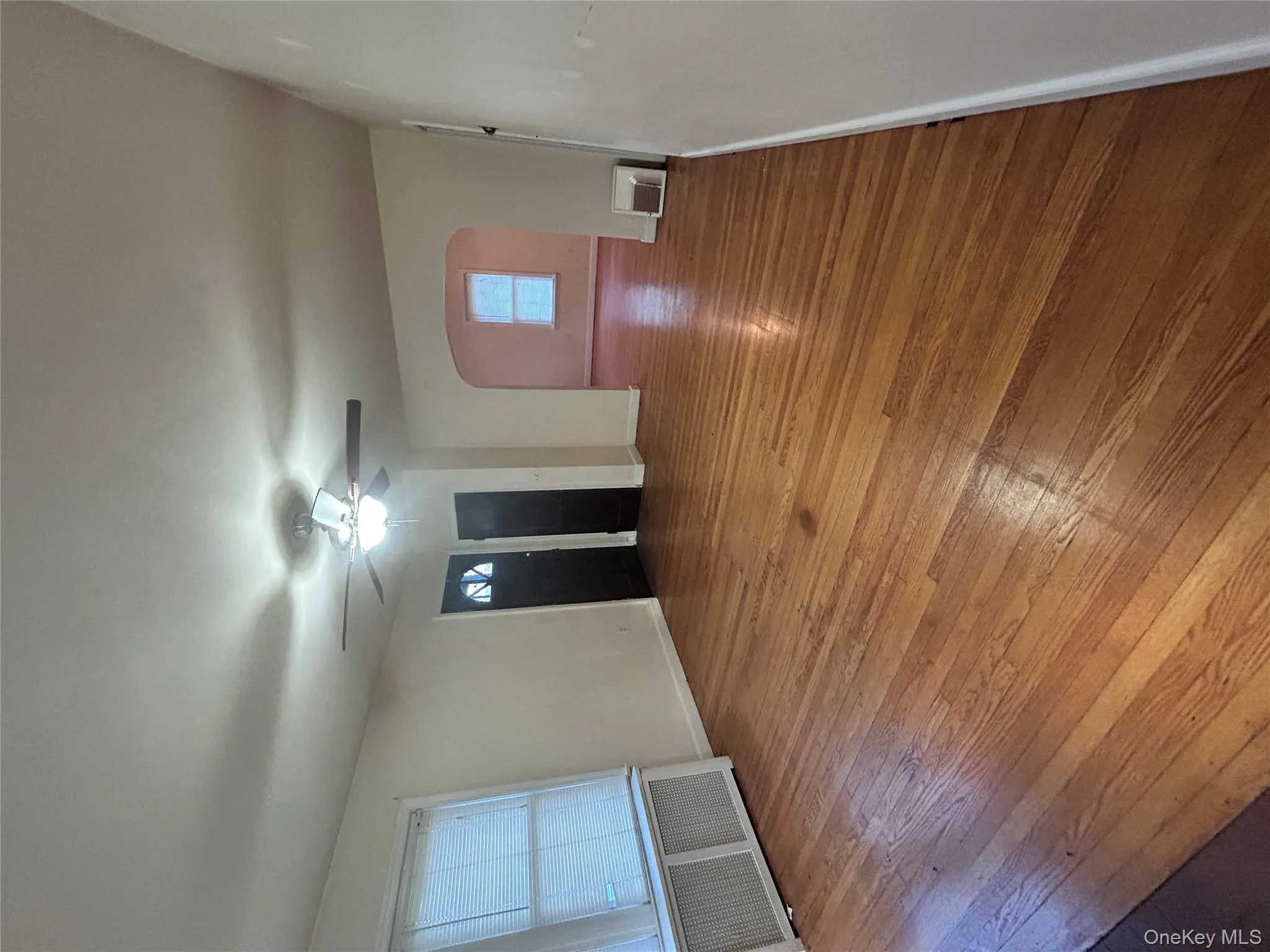 Unfurnished room with radiator, arched walkways, light wood-style flooring, and a ceiling fan Unfurnished room with radiator, arched walkways, light wood-style flooring, and a ceiling fan