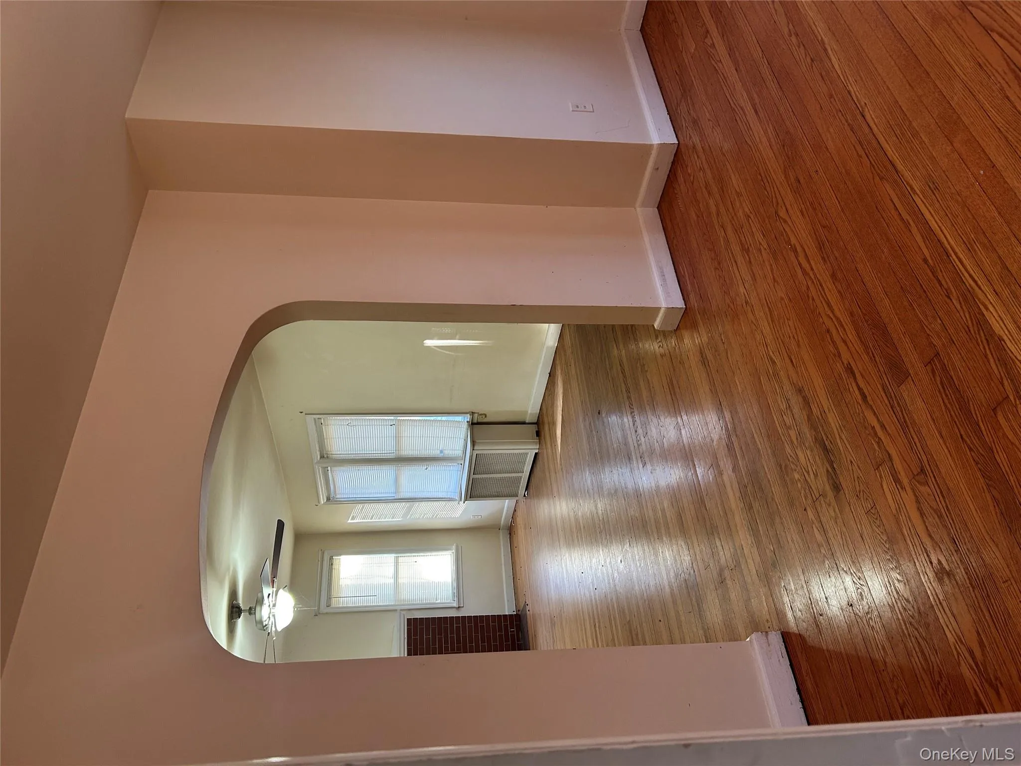 Unfurnished room with arched walkways, wood-type flooring, radiator, and a ceiling fan Unfurnished room with arched walkways, wood-type flooring, radiator, and a ceiling fan