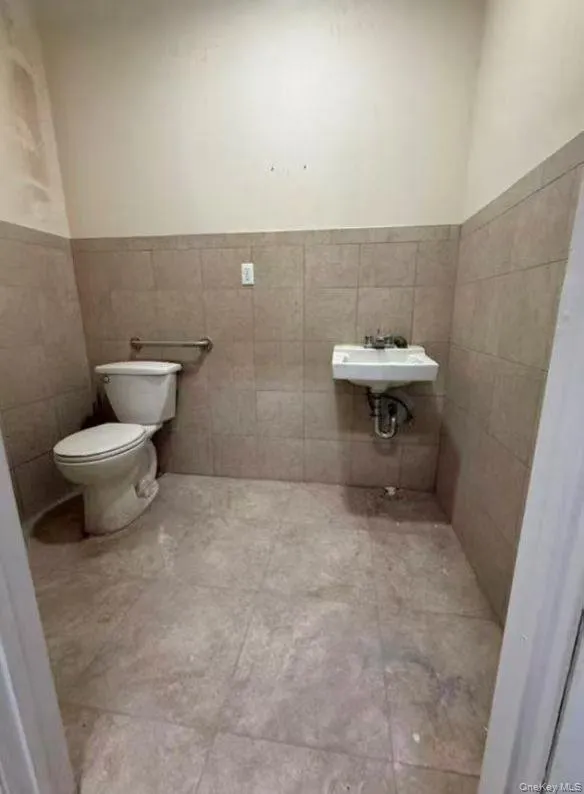 Bathroom with tile walls, wainscoting, and light tile patterned floors Bathroom with tile walls, wainscoting, and light tile patterned floors