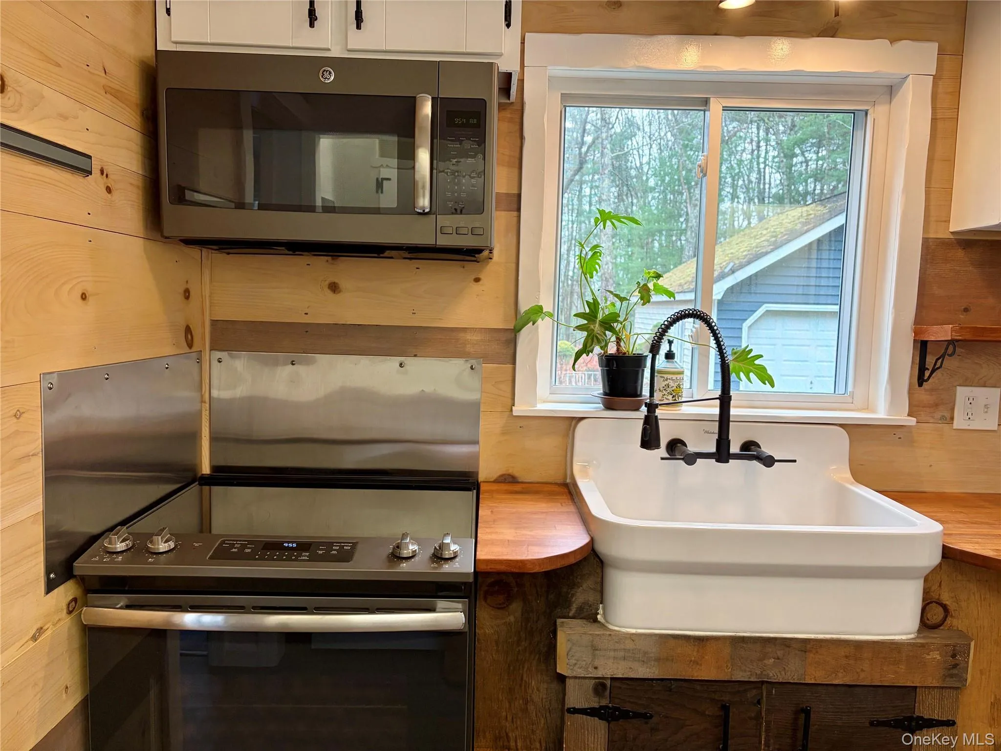 Kitchen with stainless steel appliances, wooden walls, and white cabinets Kitchen with stainless steel appliances, wooden walls, and white cabinets
