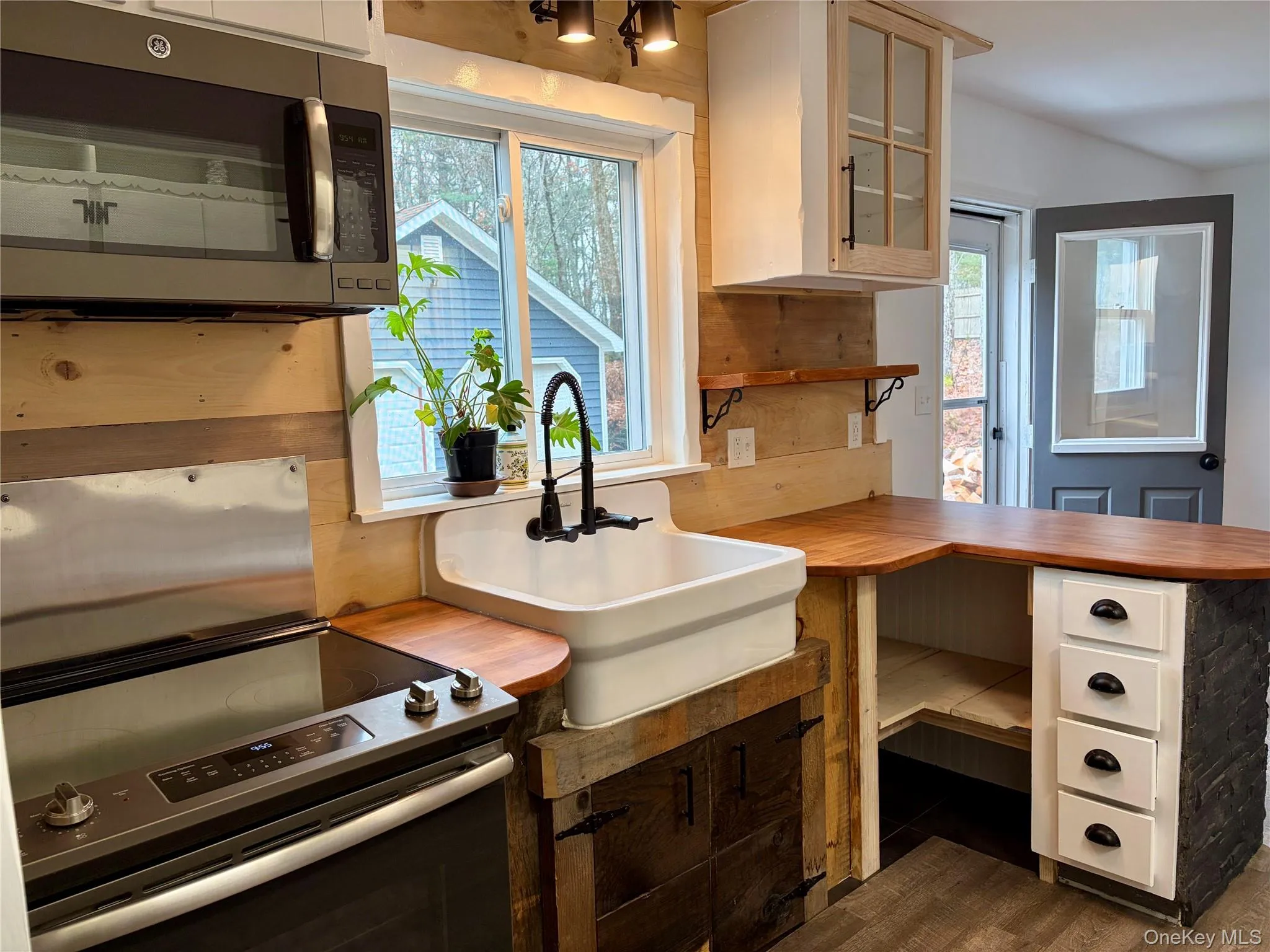Kitchen with stainless steel appliances, glass insert cabinets, a peninsula, and wood counters Kitchen with stainless steel appliances, glass insert cabinets, a peninsula, and wood counters