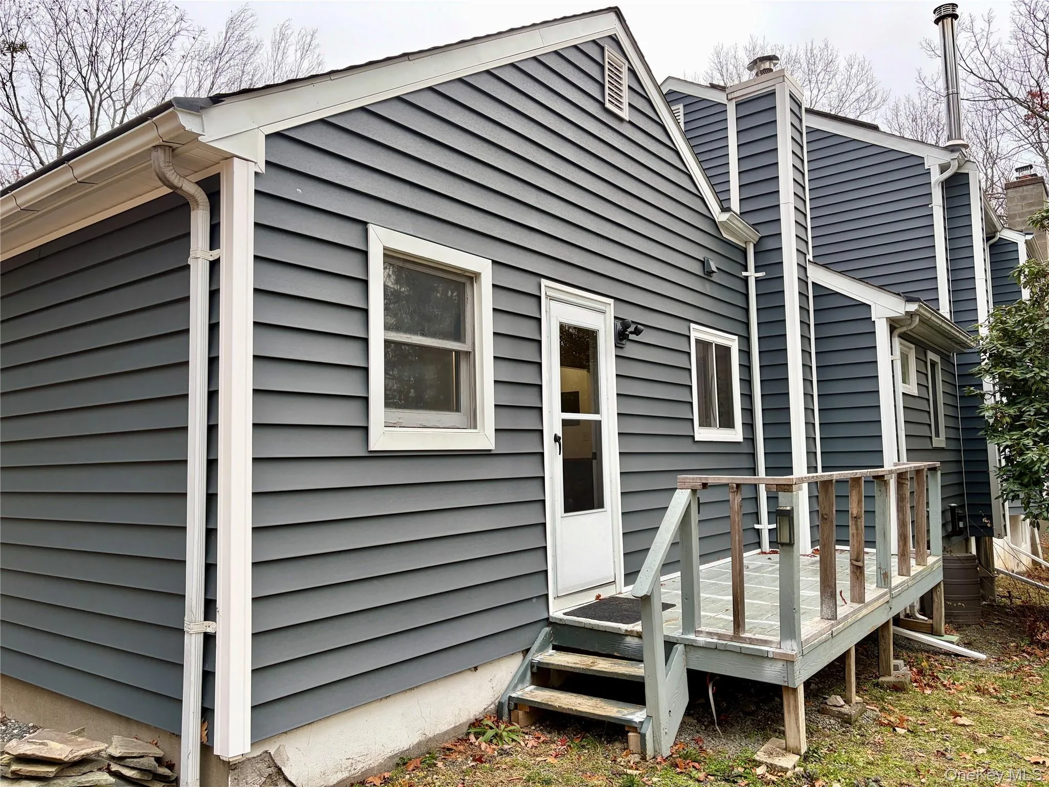 Back of house with a chimney and a wooden deck Back of house with a chimney and a wooden deck