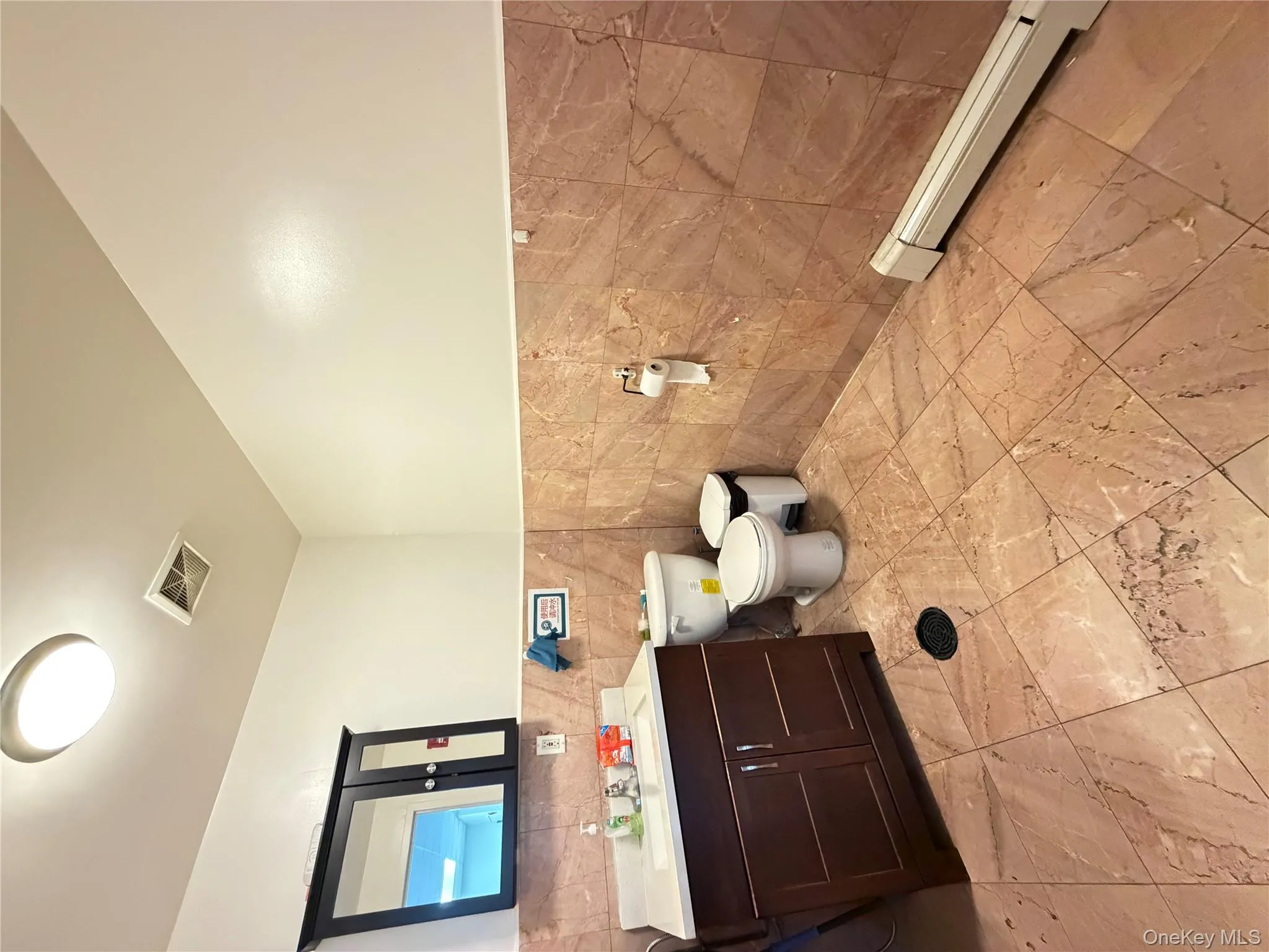 Half bath featuring baseboard heating, vanity, wainscoting, and tile walls Half bath featuring baseboard heating, vanity, wainscoting, and tile walls