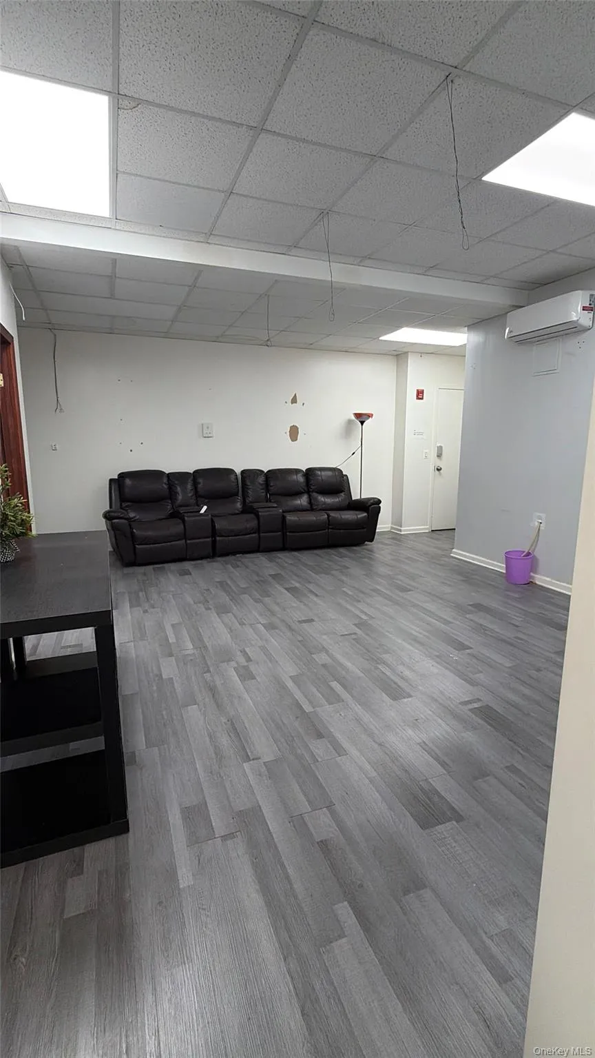 Finished below grade area featuring light wood-style floors, a wall unit AC, and a paneled ceiling Finished below grade area featuring light wood-style floors, a wall unit AC, and a paneled ceiling