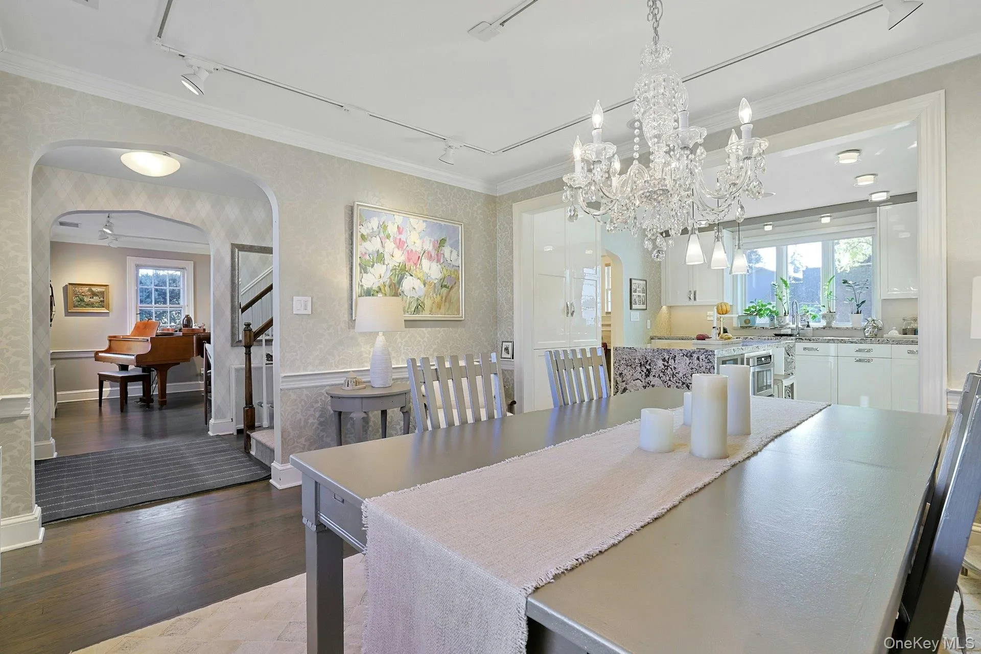 Dining area with arched walkways, wallpapered walls, track lighting, crown molding, and light wood-type flooring Dining area with arched walkways, wallpapered walls, track lighting, crown molding, and light wood-type flooring
