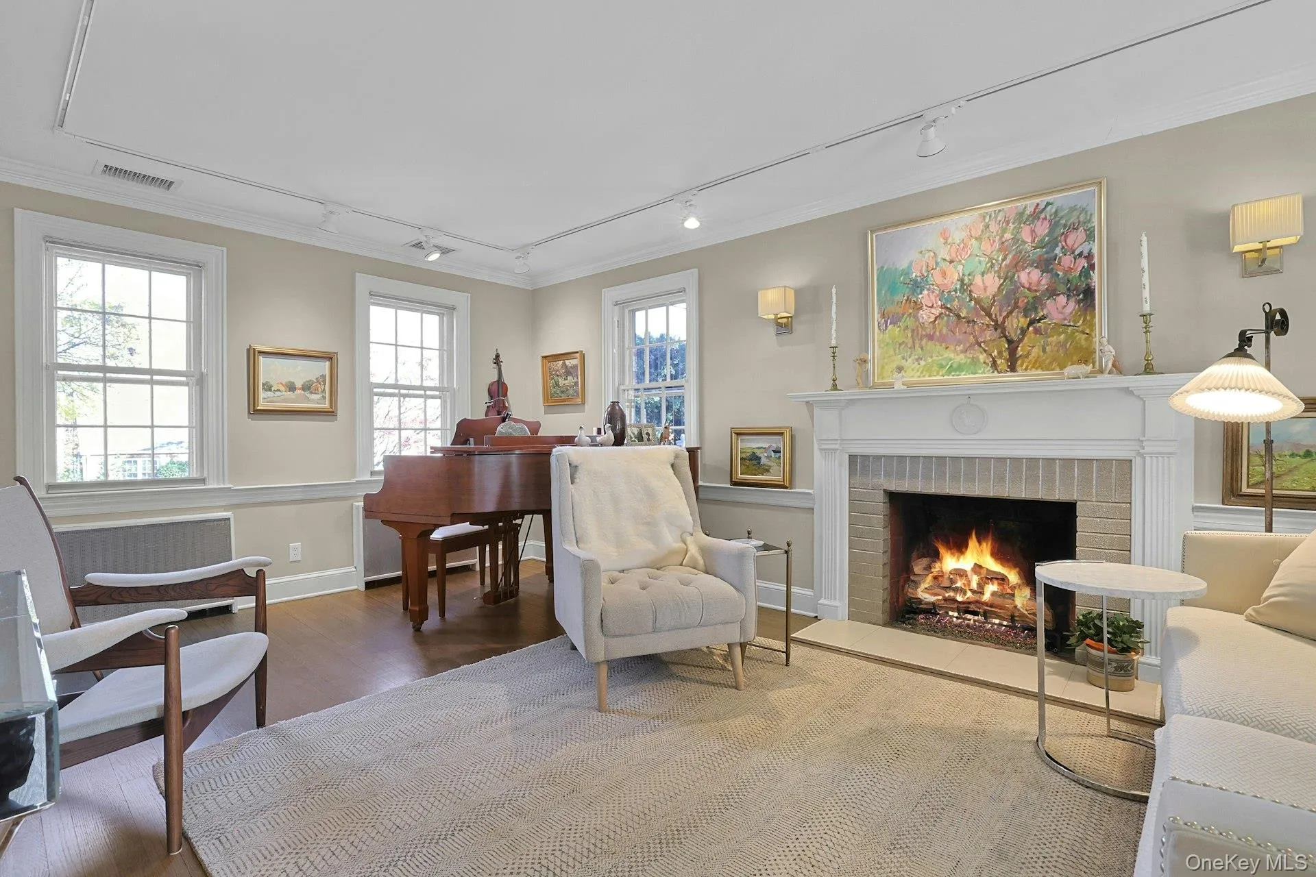 Living area featuring rail lighting, wood finished floors, a brick fireplace, and ornamental molding Living area featuring rail lighting, wood finished floors, a brick fireplace, and ornamental molding