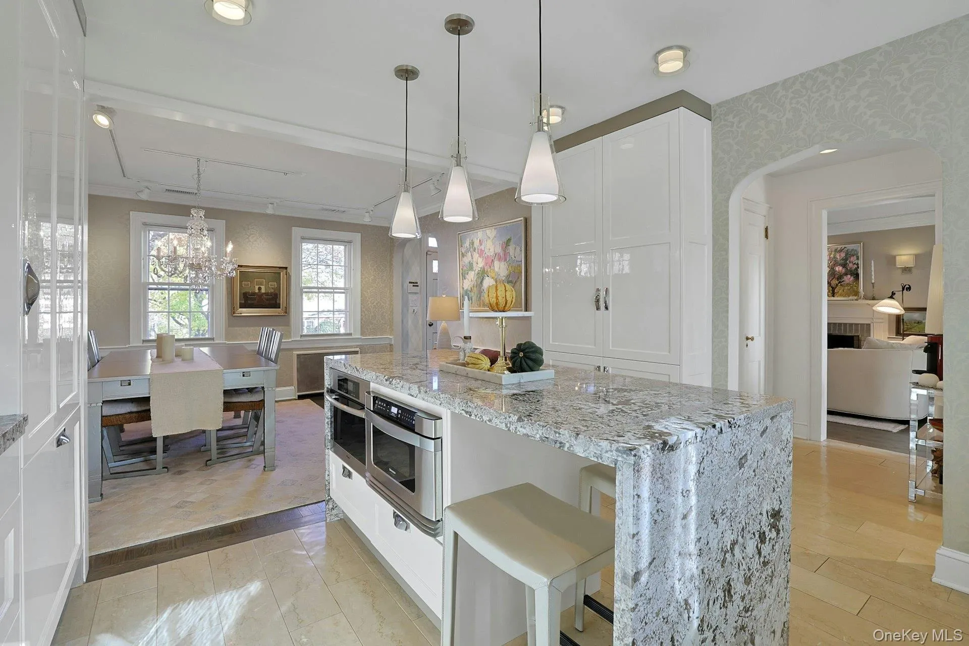 Kitchen with white cabinets, light stone countertops, hanging light fixtures, and a breakfast bar area Kitchen with white cabinets, light stone countertops, hanging light fixtures, and a breakfast bar area