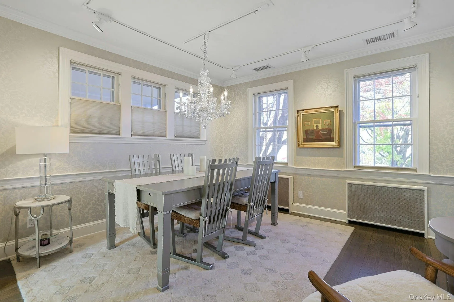 Dining room with rail lighting, wallpapered walls, ornamental molding, a chandelier, and radiator heating unit Dining room with rail lighting, wallpapered walls, ornamental molding, a chandelier, and radiator heating unit