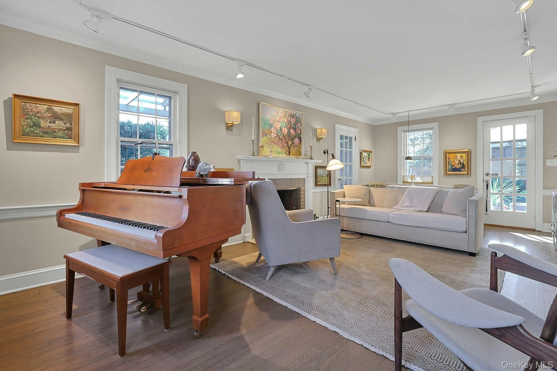 Living room featuring rail lighting, a brick fireplace, wood finished floors, and ornamental molding Living room featuring rail lighting, a brick fireplace, wood finished floors, and ornamental molding