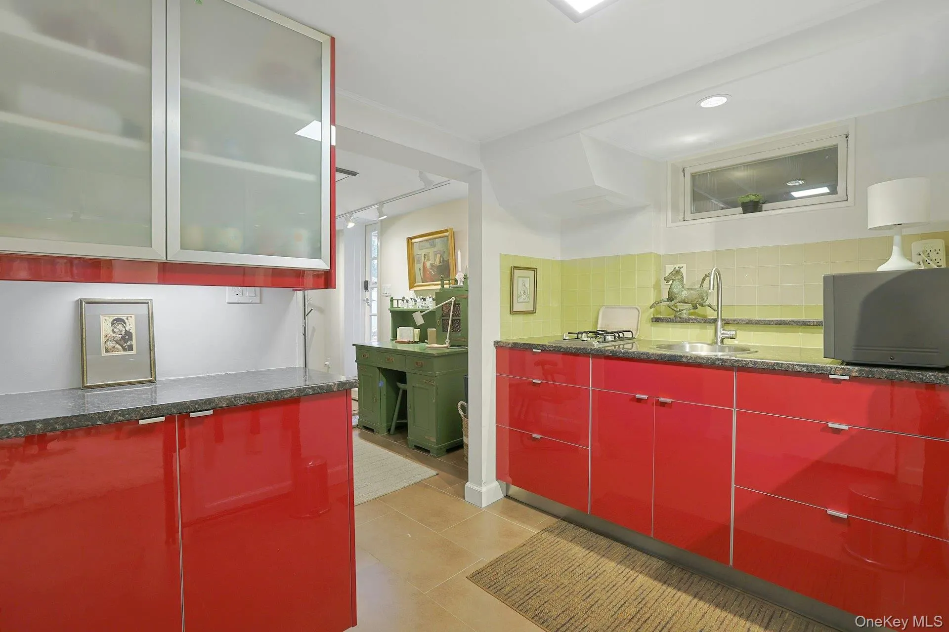 Bar featuring red cabinetry, track lighting, tasteful backsplash, glass insert cabinets, and dark stone countertops Bar featuring red cabinetry, track lighting, tasteful backsplash, glass insert cabinets, and dark stone countertops