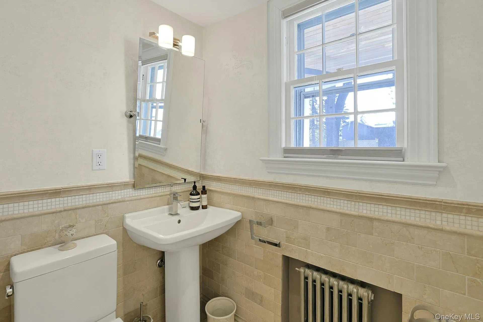 Half bathroom featuring wainscoting, radiator heating unit, and tile walls Half bathroom featuring wainscoting, radiator heating unit, and tile walls