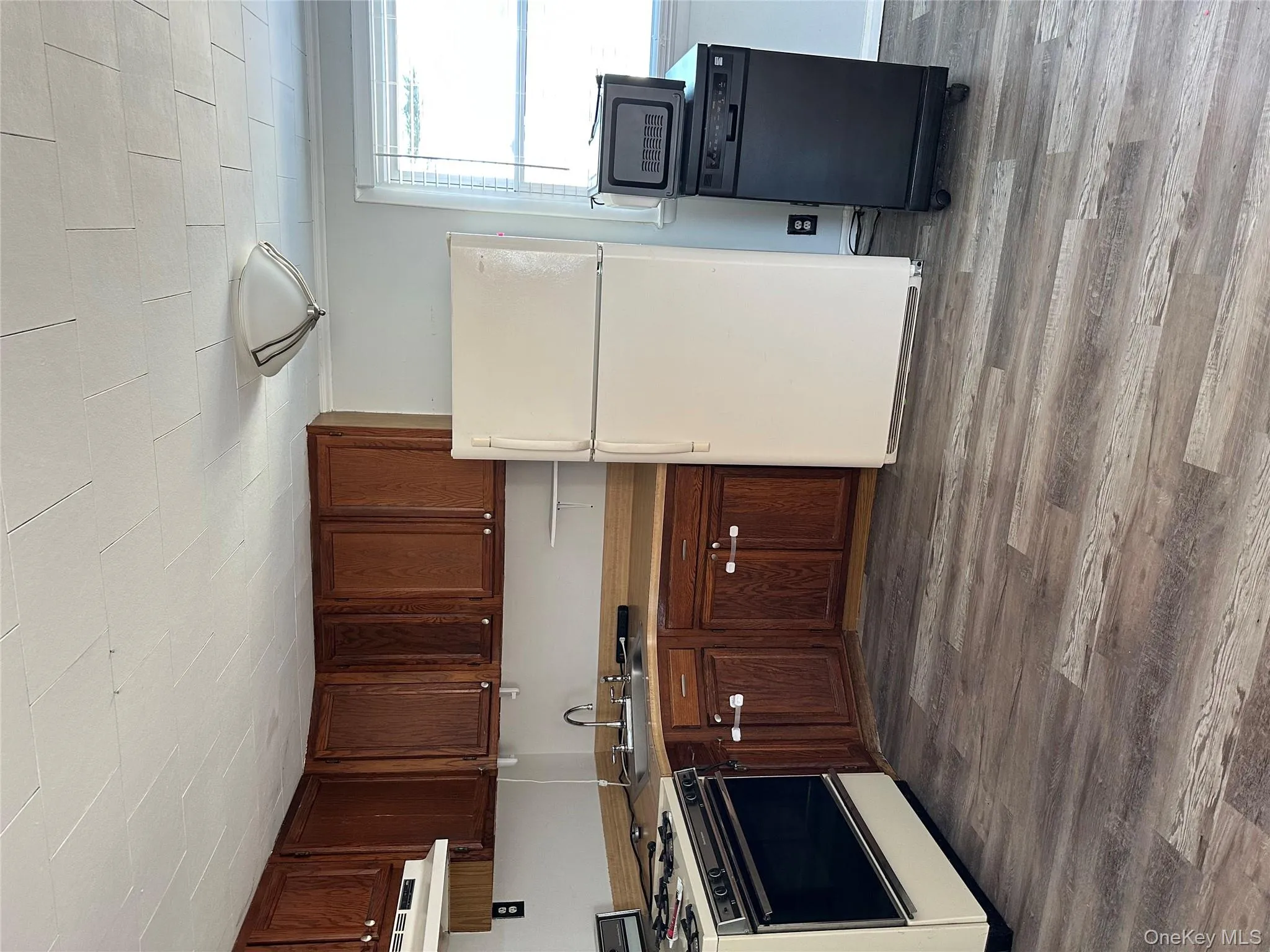 Kitchen with stove, white fridge, dark wood-style flooring, and light countertops Kitchen with stove, white fridge, dark wood-style flooring, and light countertops
