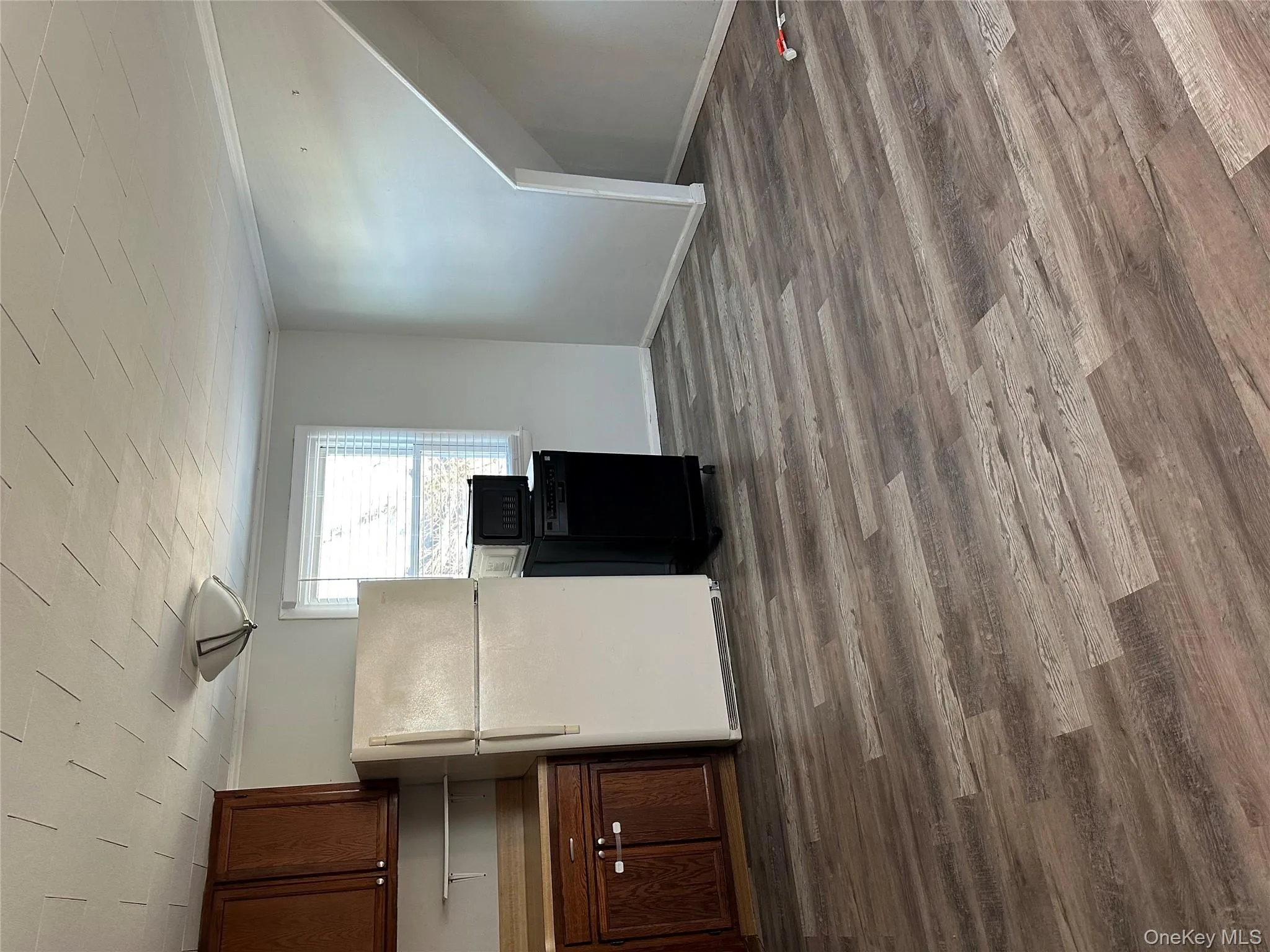 Kitchen featuring refrigerator, crown molding, dark wood-style floors, dishwasher, and light countertops Kitchen featuring refrigerator, crown molding, dark wood-style floors, dishwasher, and light countertops