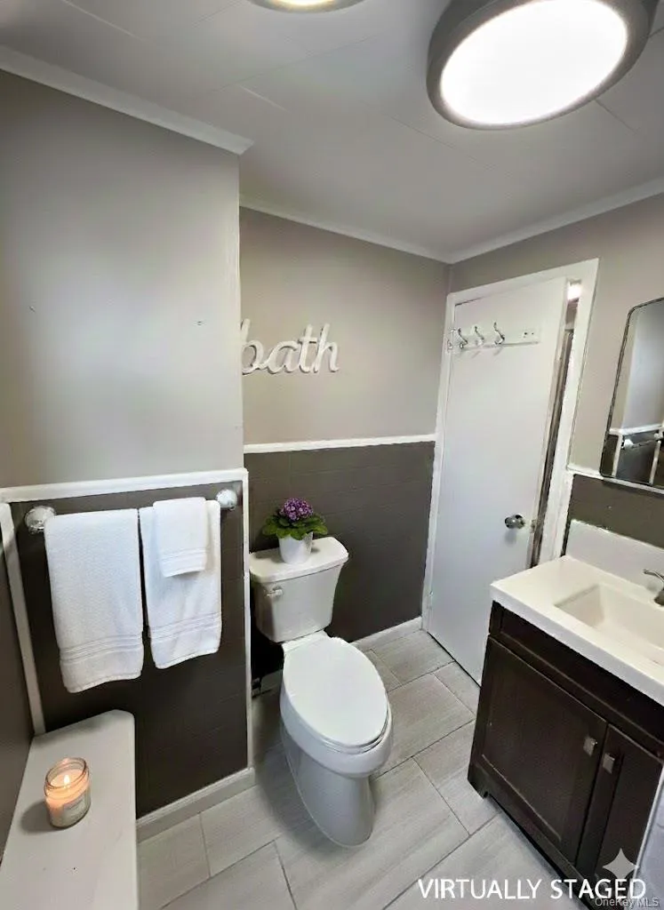 Half bathroom with vanity, ornamental molding, and wainscoting Half bathroom with vanity, ornamental molding, and wainscoting