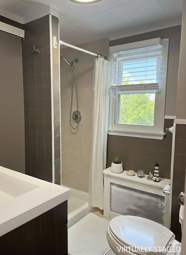 Bathroom featuring vanity, a stall shower, and tile walls Bathroom featuring vanity, a stall shower, and tile walls