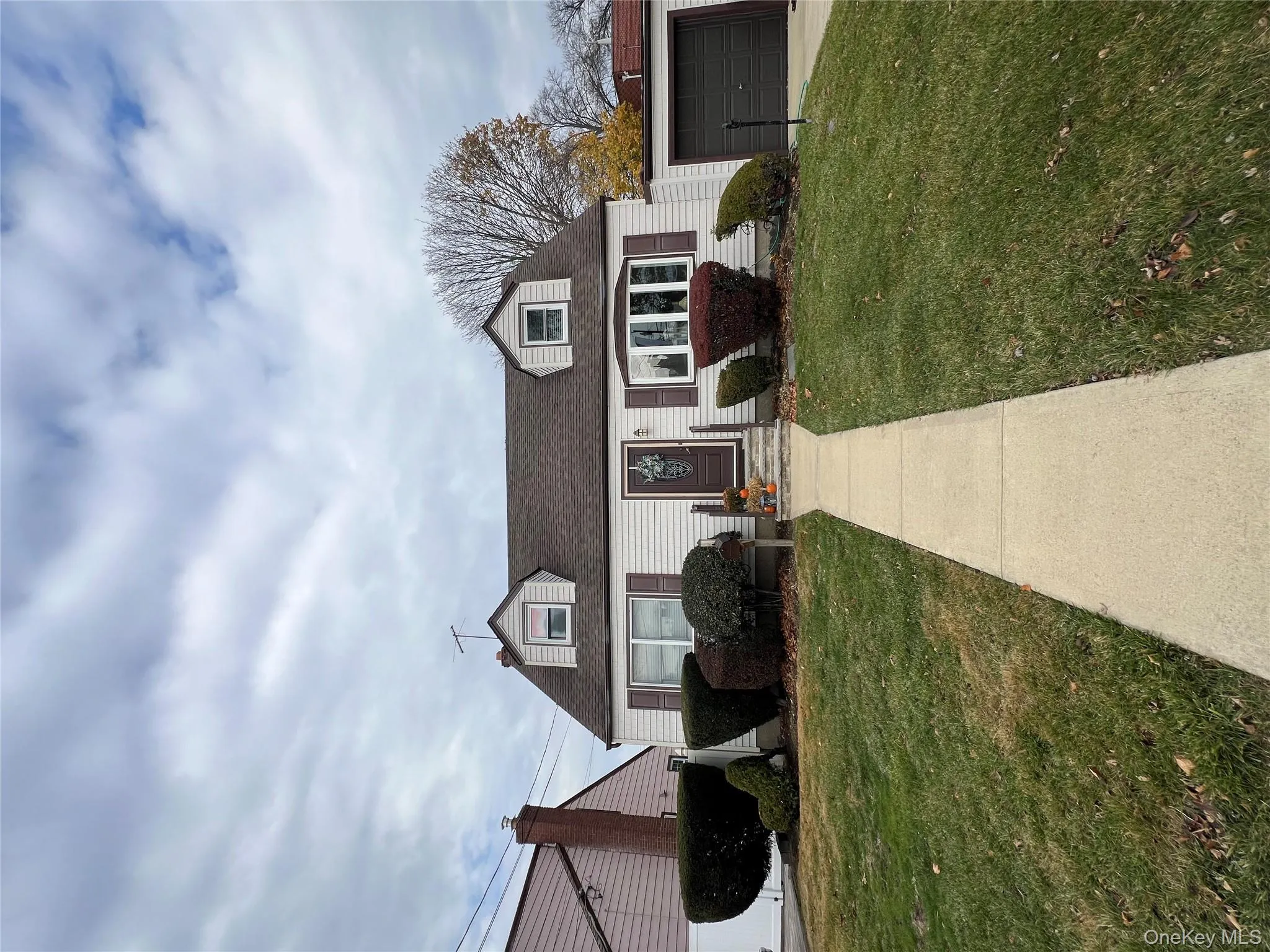 View of front of house with a front lawn, a shingled roof, and a garage View of front of house with a front lawn, a shingled roof, and a garage