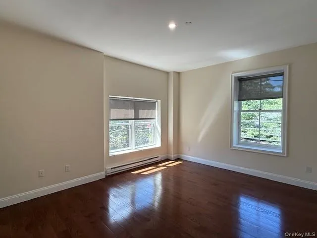 Spare room with dark wood finished floors, healthy amount of natural light, a baseboard heating unit, and recessed lighting Spare room with dark wood finished floors, healthy amount of natural light, a baseboard heating unit, and recessed lighting
