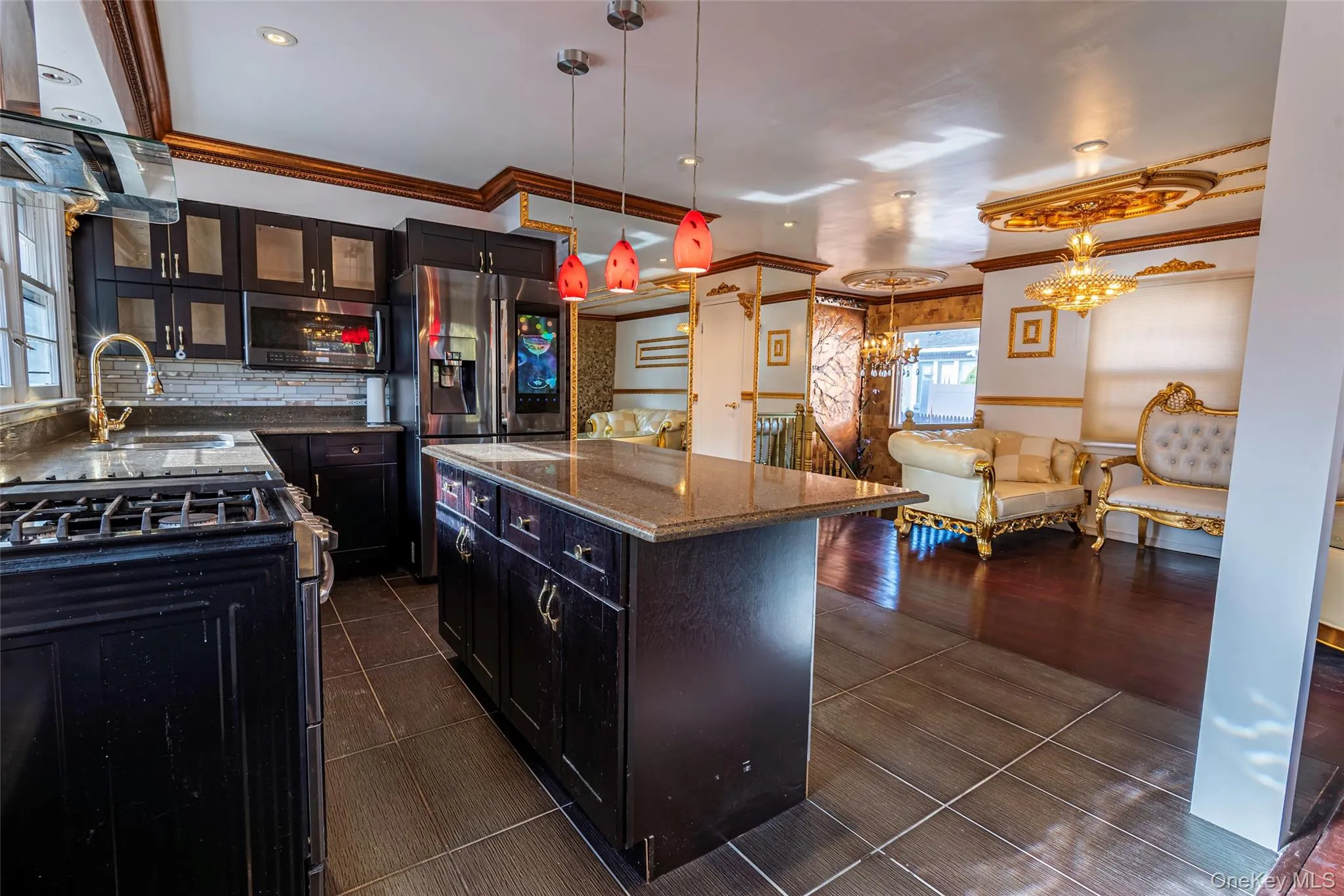 Kitchen featuring appliances with stainless steel finishes, exhaust hood, dark stone countertops, pendant lighting, and glass insert cabinets Kitchen featuring appliances with stainless steel finishes, exhaust hood, dark stone countertops, pendant lighting, and glass insert cabinets