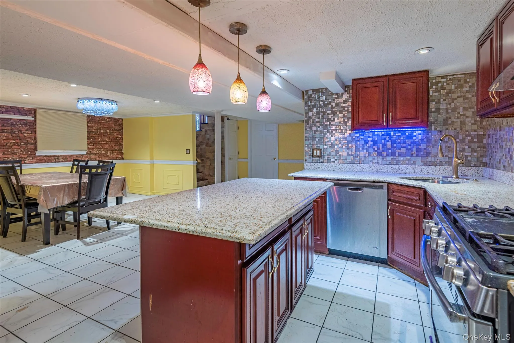 Kitchen with a center island, decorative light fixtures, appliances with stainless steel finishes, light stone countertops, and a textured ceiling Kitchen with a center island, decorative light fixtures, appliances with stainless steel finishes, light stone countertops, and a textured ceiling
