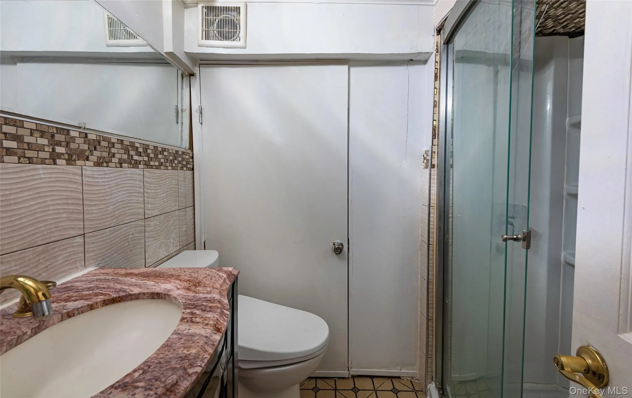 Bathroom with a shower stall, vanity, and tile walls Bathroom with a shower stall, vanity, and tile walls