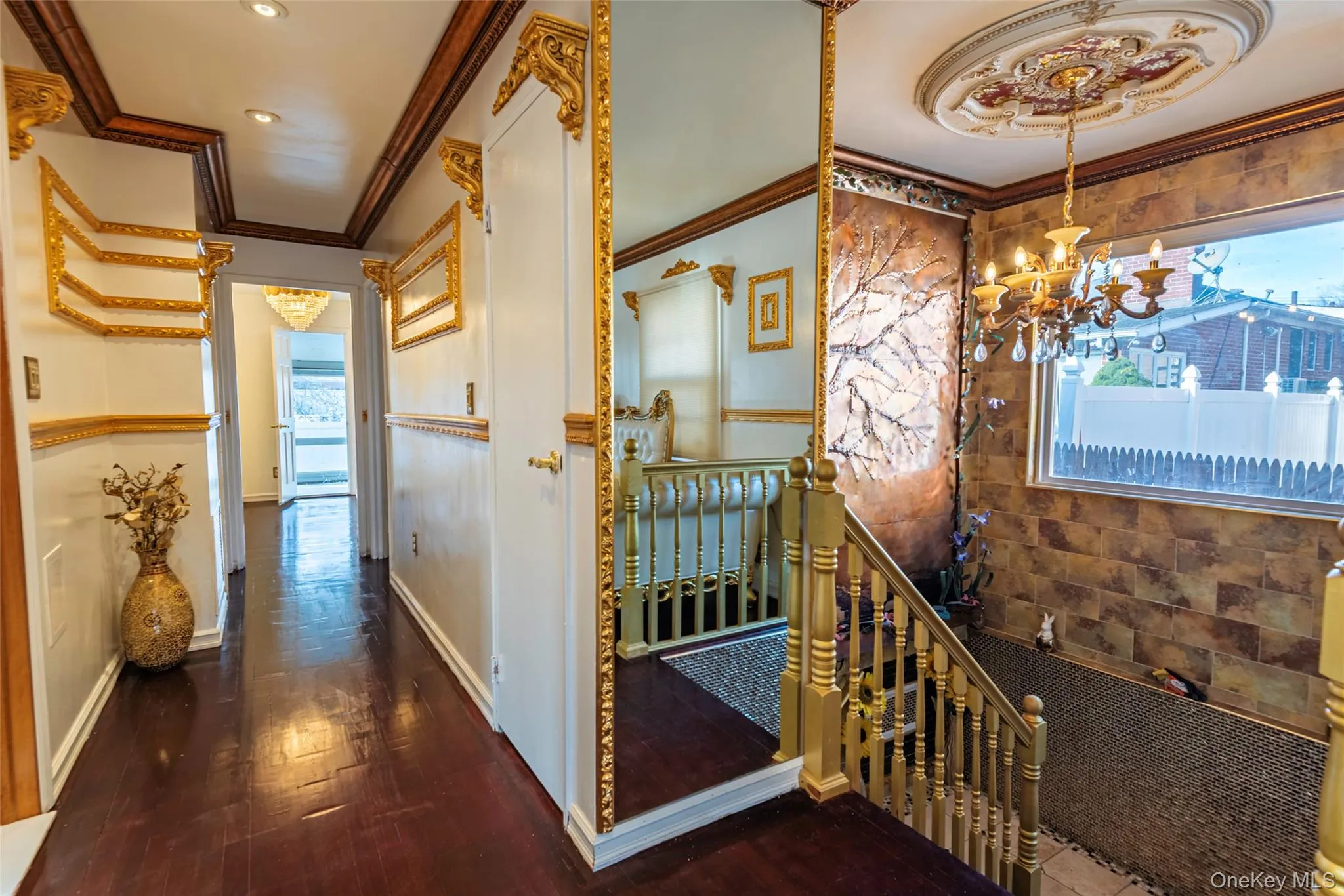 Corridor featuring an upstairs landing, ornamental molding, dark wood-style floors, healthy amount of natural light, and a chandelier Corridor featuring an upstairs landing, ornamental molding, dark wood-style floors, healthy amount of natural light, and a chandelier