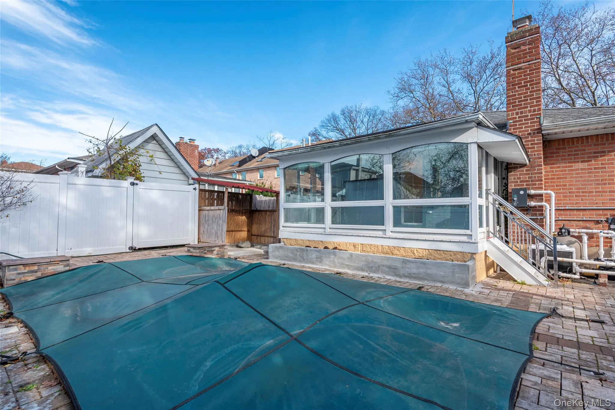 Back of property featuring a sunroom, a chimney, and a patio Back of property featuring a sunroom, a chimney, and a patio