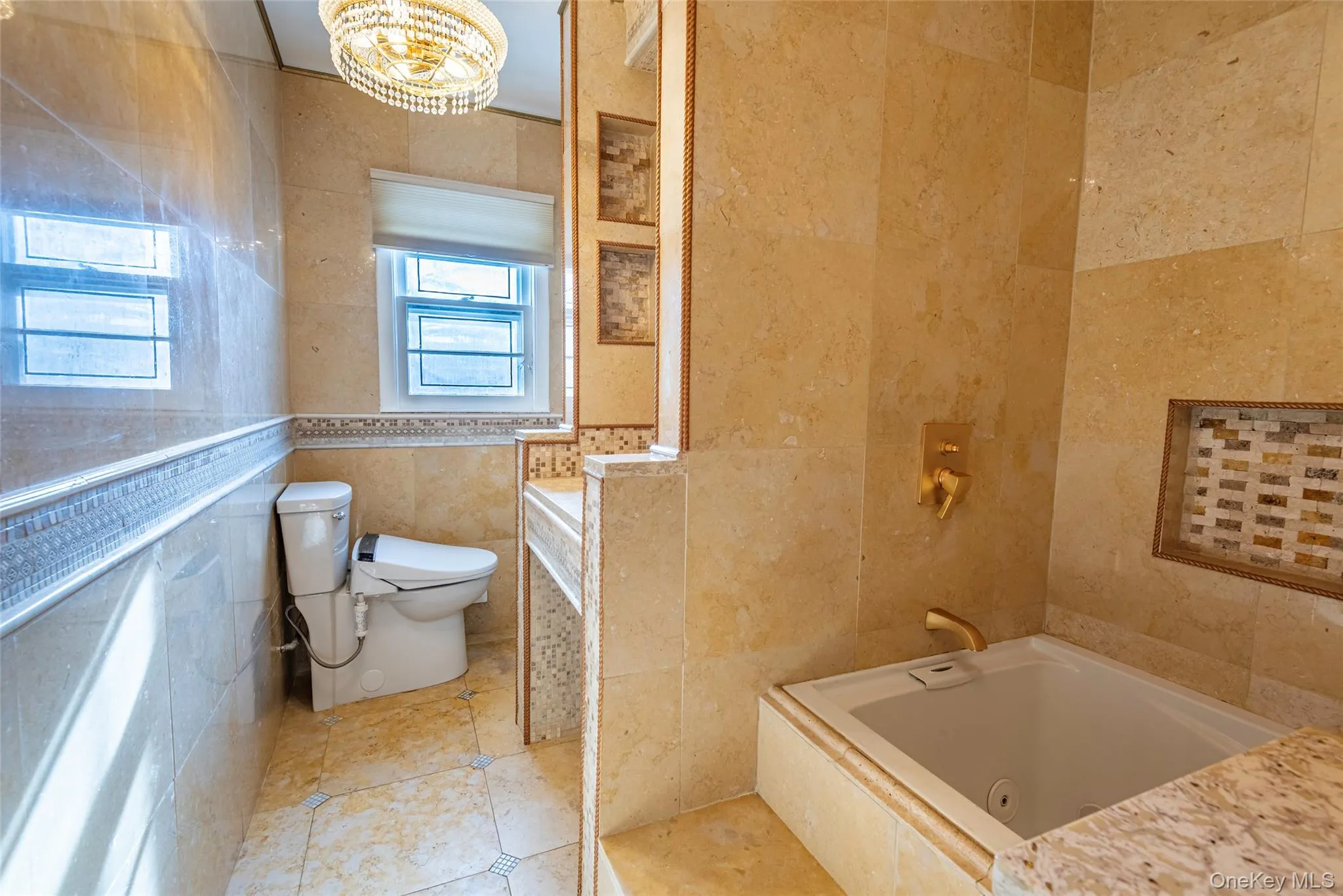 Bathroom with tile walls, a tub with jets, tile patterned floors, and a chandelier Bathroom with tile walls, a tub with jets, tile patterned floors, and a chandelier