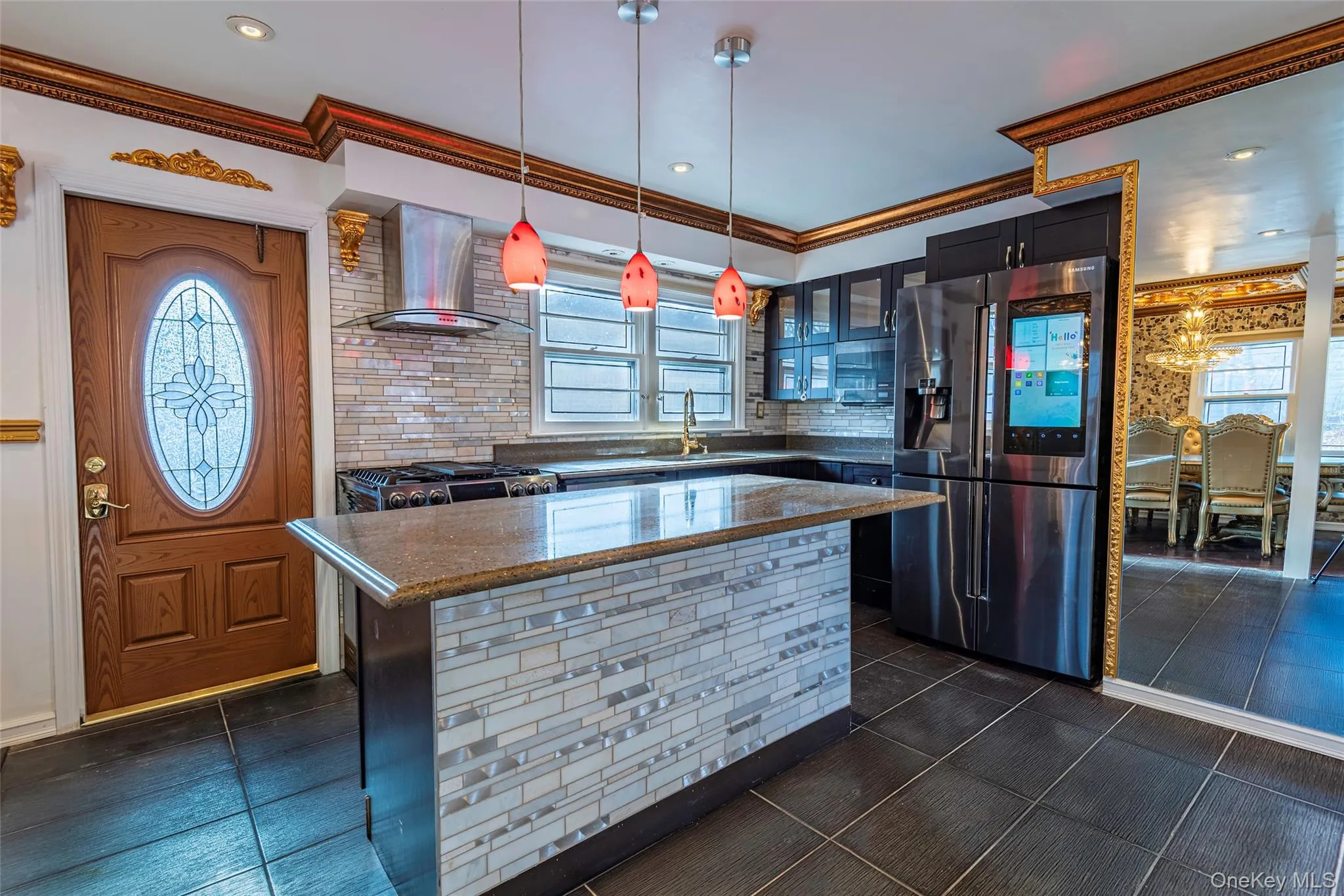 Kitchen featuring stainless steel appliances, dark stone countertops, decorative backsplash, healthy amount of natural light, and ornamental molding Kitchen featuring stainless steel appliances, dark stone countertops, decorative backsplash, healthy amount of natural light, and ornamental molding