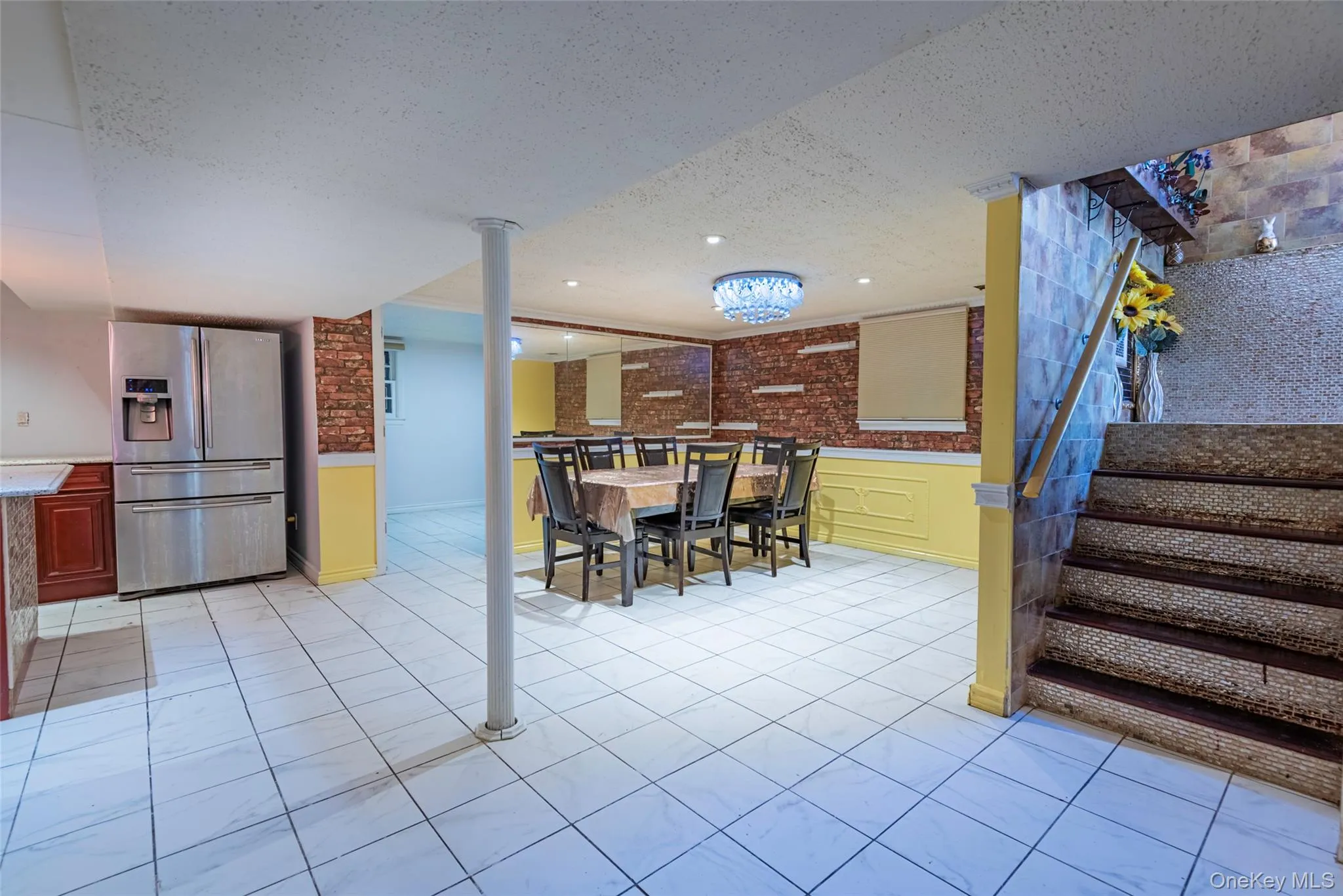 Dining room with a wainscoted wall, a textured ceiling, stairway, and brick wall Dining room with a wainscoted wall, a textured ceiling, stairway, and brick wall