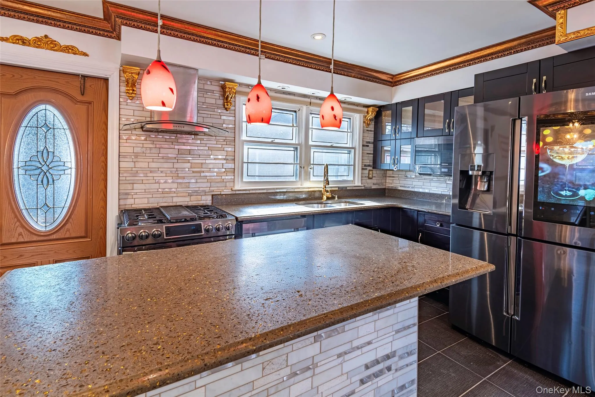 Kitchen with stainless steel appliances, decorative backsplash, hanging light fixtures, wall chimney exhaust hood, and crown molding Kitchen with stainless steel appliances, decorative backsplash, hanging light fixtures, wall chimney exhaust hood, and crown molding